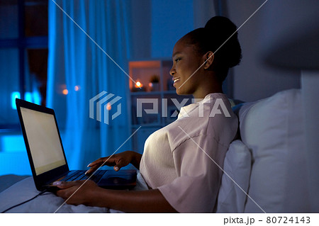 woman with laptop in bed at home at night 80724143