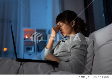 stressed woman with laptop working in bed at night stressed woman with laptop working in bed at night 80724500