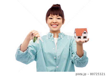 smiling asian woman holding house model and keys 80725321