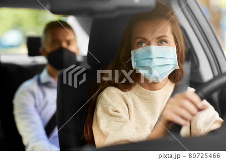 female driver in mask driving car with passenger 80725466