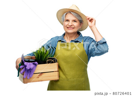 smiling senior woman with garden tools in box 80726401