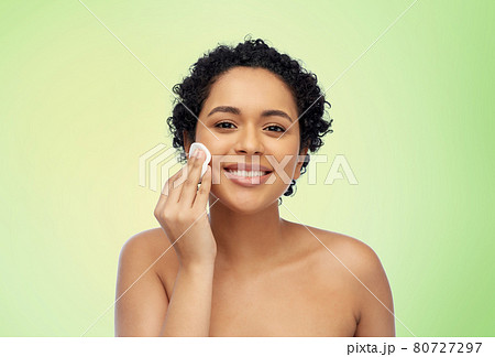 happy african woman cleaning face with cotton pad happy african woman cleaning face with cotton pad 80727297