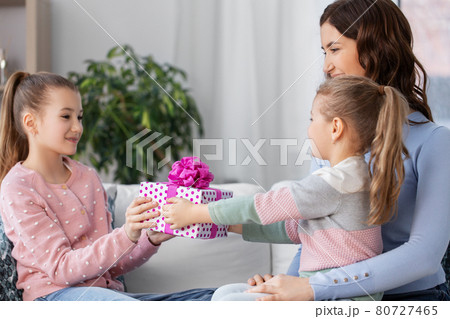 girl giving present to younger sister at home 80727465