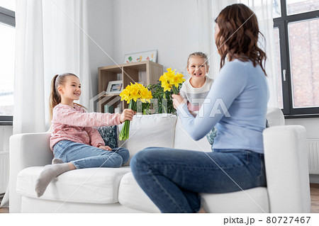 daughters giving daffodil flowers to happy mother 80727467
