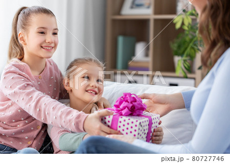 daughters giving present to happy mother 80727746