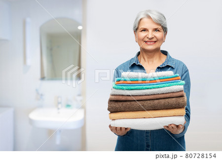 smiling senior woman with clean bath towels 80728154