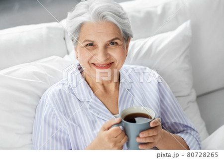 old woman with cup of coffee in bed at home 80728265