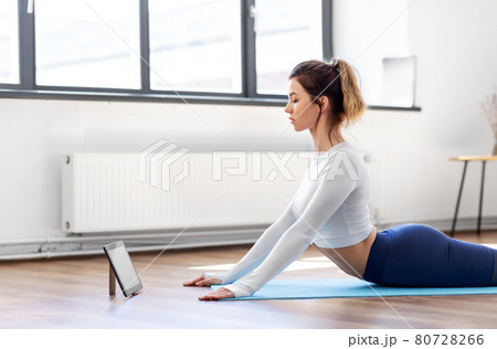 woman with tablet pc doing yoga at home woman with tablet pc doing yoga at home 80728266