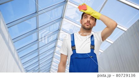 tired male cleaner with sponge in glasshouse tired male cleaner with sponge in glasshouse 80729136
