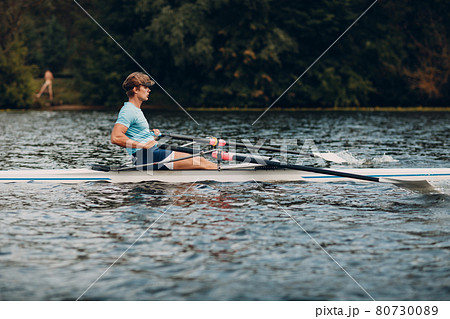 Sportsman single scull man rower rowing on boat Sportsman single scull man rower rowing on boat 80730089