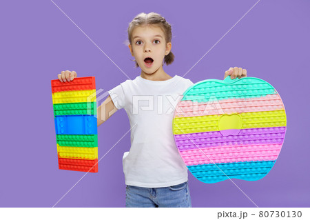 Surprised kid holding huge apple anti stress bubble. motor skills. pop it fun. child holding color popit fidget Surprised kid holding huge apple anti stress bubble. motor skills. pop it fun. child holding color popit fidget 80730130