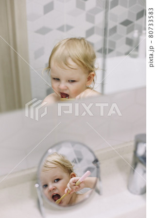reflection in the mirror of a little funny girl brushing her teeth reflection in the mirror of a little funny girl brushing her teeth 80733583