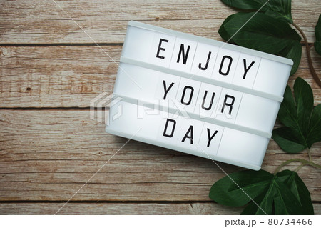Enjoy Your Day text on lightbox on wooden background Enjoy Your Day text on lightbox on wooden background 80734466