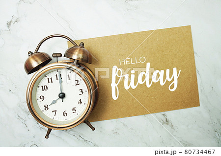 Hello Friday typography text on paper card with alarm clock on marble background Hello Friday typography text on paper card with alarm clock on marble background 80734467