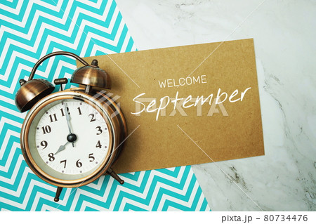Welcome September typography text on paper card with alarm clock on marble background 80734476