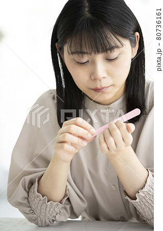 窓辺で爪やすりで爪のお手入れをする女性 80736161