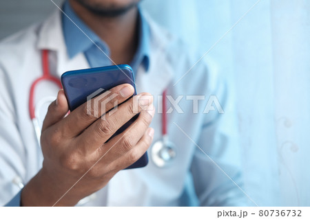 doctor in white coat using a smartphone. 80736732