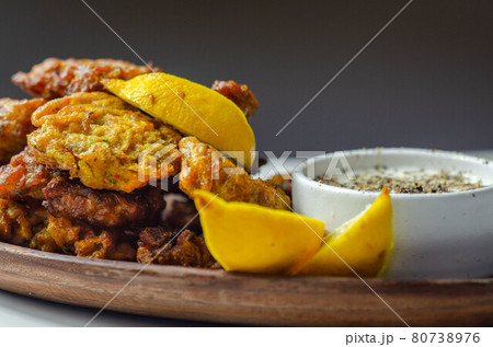 Delicious onion bhaji fritters served on wooden plate with white dip Delicious onion bhaji fritters served on wooden plate with white dip 80738976