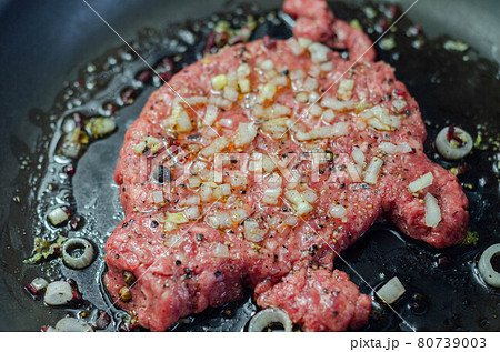 Minced meat with fresh spring onions and spices in the shape of a pig, fried in a pan, a creatively prepared burger in an interesting shape Minced meat with fresh spring onions and spices in the shape of a pig, fried in a pan, a creatively prepared burger in an interesting shape 80739003