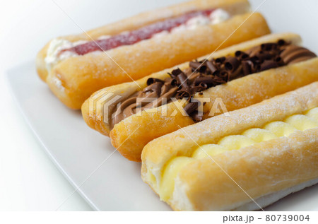 Mixed finger donuts filling chocolate, custard, jam and whipped cream, eclairs in different flavors 80739004