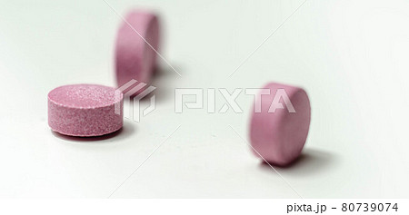 Purple pills scattered on a white background, food supplements which includes acai berries Purple pills scattered on a white background, food supplements which includes acai berries 80739074