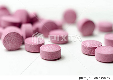Purple pills scattered on a white background, food supplements which includes acai berries Purple pills scattered on a white background, food supplements which includes acai berries 80739075