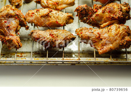 Raw chicken wings with a rendang style rub made with chilli and garlic on the grill tray 80739656