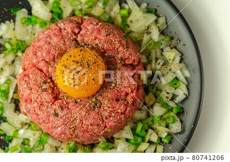Beef steak tartare with raw egg yolk and onion with chive 80741206