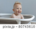 little boy is sitting in a bath and laughing 80743610