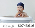 A small child rushes his teeth while sitting in the bathroom 80743616