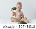 little boy holds avocado in his hands and smiles. 80743618