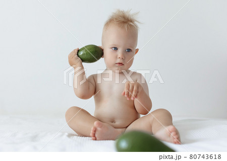 little boy holds avocado in his hands and smiles. 80743618