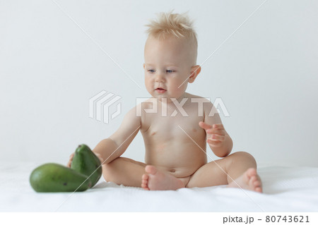 little boy holds avocado in his hands and smiles. 80743621