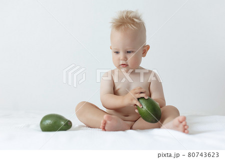 little boy holds avocado in his hands and smiles 80743623