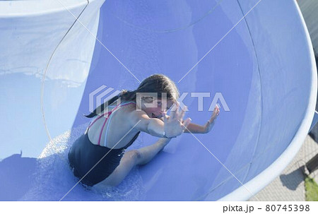 Happy kid on water slide at water park. Water slide with flowing splash water at aqua park. Summer aqua park holiday. Vacation concept Happy kid on water slide at water park. Water slide with flowing splash water at aqua park. Summer aqua park holiday. Vacation concept 80745398