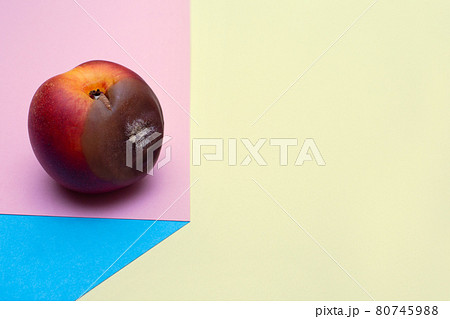 Spoiled food. Rotten nectarine on a colored background. Mold on food leftovers. Copy Space. Place for text. Unpleasant view. 80745988