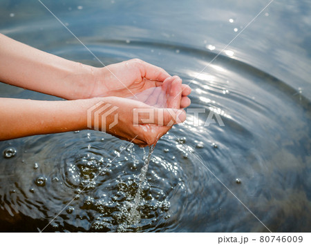 Person taking raw unfiltered water from a lake by hands 80746009
