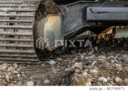 Heavy excavator (digger machine) track detail, some stones in foreground. Abstract industrial / construction background. Heavy excavator (digger machine) track detail, some stones in foreground. Abstract industrial / construction background. 80746971