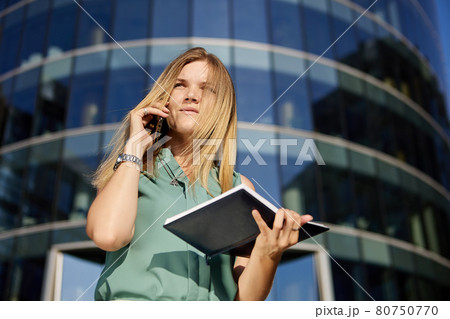 Business woman makes an appointment by phone outdoors on the go. Business woman makes an appointment by phone outdoors on the go. 80750770