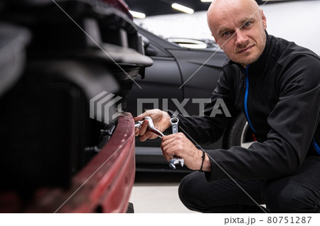 Mechanic in service checking and repairing car bumper Mechanic in service checking and repairing car bumper 80751287