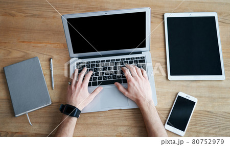 View from the top, hands working with laptop and smartphone on wooden table 80752979