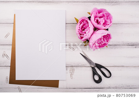 White paper on the wooden desk with flower and scissors White paper on the wooden desk with flower and scissors 80753069