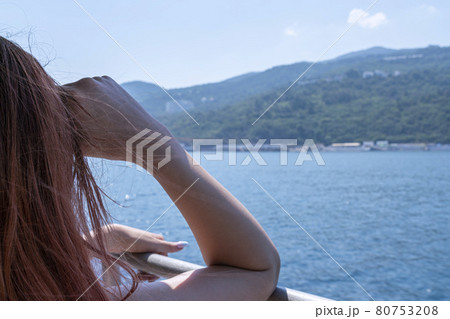 a young woman looks at the shore from a ship 80753208