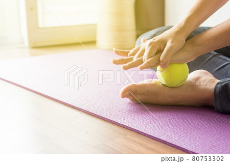 Woman massage with tennis ball to her foot in bedroom,Feet soles massage for plantar fasciitis Woman massage with tennis ball to her foot in bedroom,Feet soles massage for plantar fasciitis 80753302