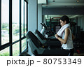Side view of beautiful girl running on treadmill at gym 80753349