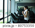 Side view of beautiful girl running on treadmill at gym 80753350