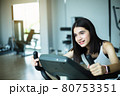 Fit young girl using exercise bike at the gym. Fitness female using air bike at gym. 80753351