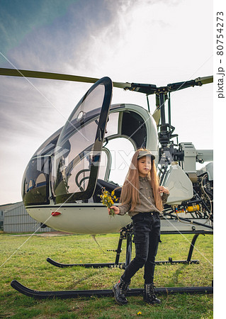 Preteen girl with bouquet of wildflowers standing near helicopter Preteen girl with bouquet of wildflowers standing near helicopter 80754273