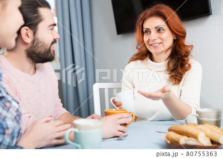 Mature woman with daughter talking at table with cup of tea Mature woman with daughter talking at table with cup of tea 80755363