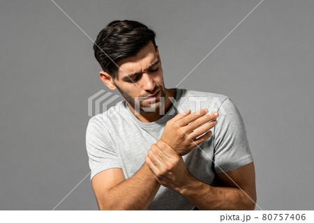Young Caucasian man having wrist pain, studio shot in isolated gray background 80757406